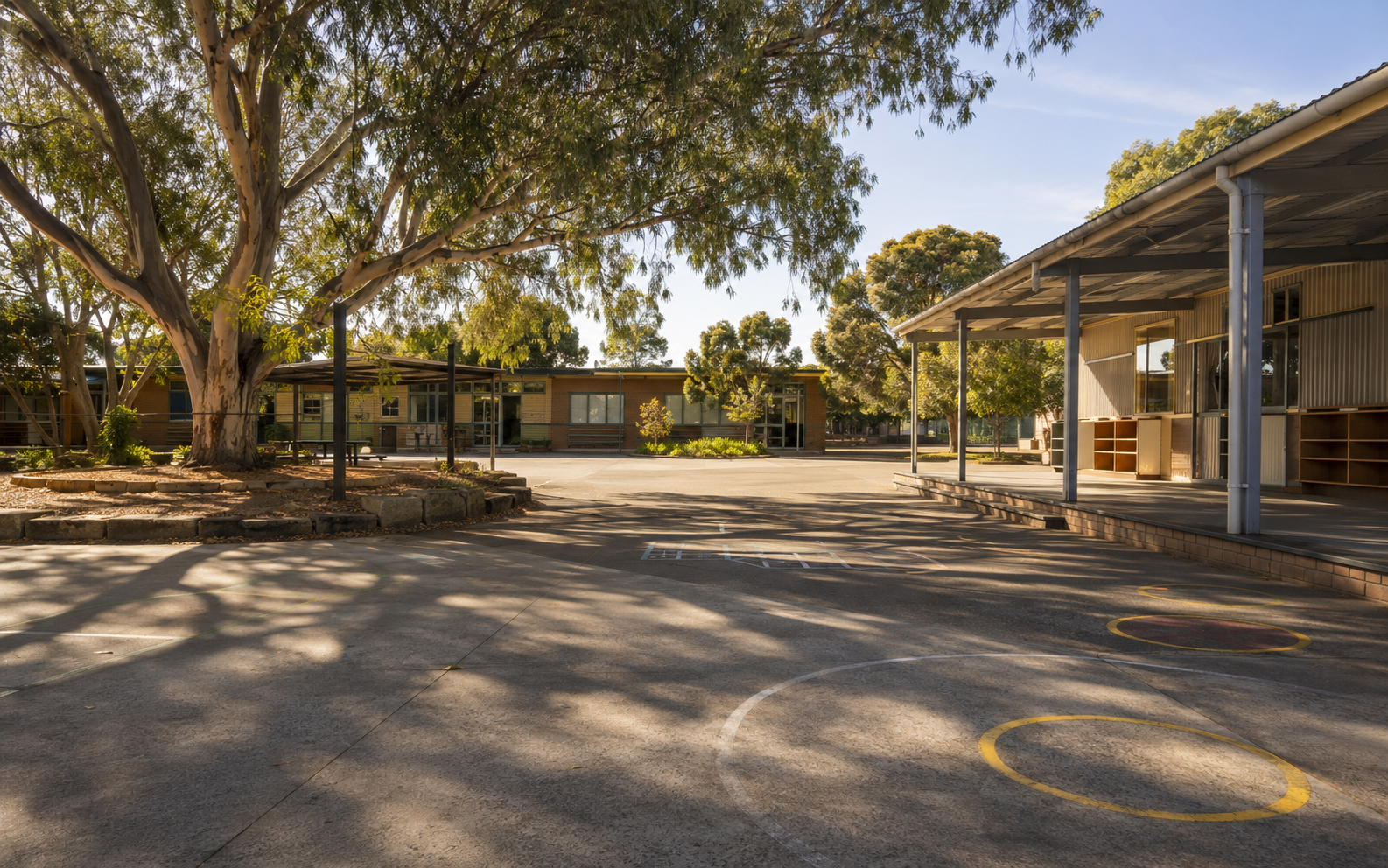 An Australian schoolyard showing shade, open surfaces, play markings, buildings and outdoor infrastructure